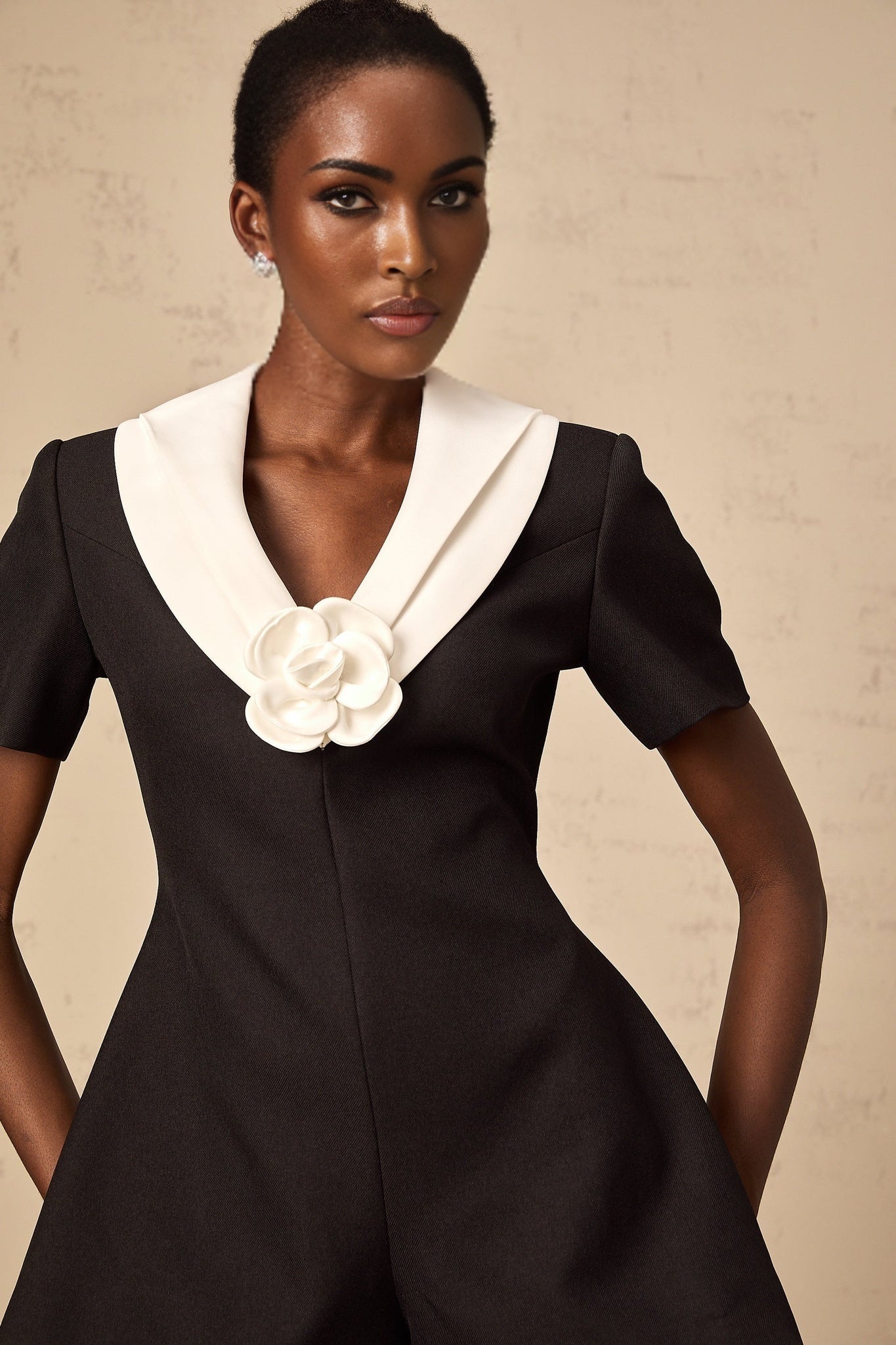 A woman wearing a colorblocked jumpsuit with floral appliqués featuring contrasting shades and a fitted silhouette