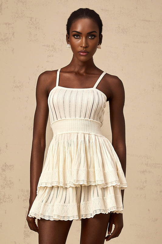 A woman wearing a creamwhite matching set consisting of a shirred crochetknit top and culottes The top has a sleeveless design with a textured pattern while the culottes are loose fitting and fall below the knee