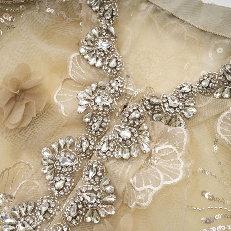 A woman wearing a delicate semi sheer jacket with floral beaded details in a light luxurious organza fabric