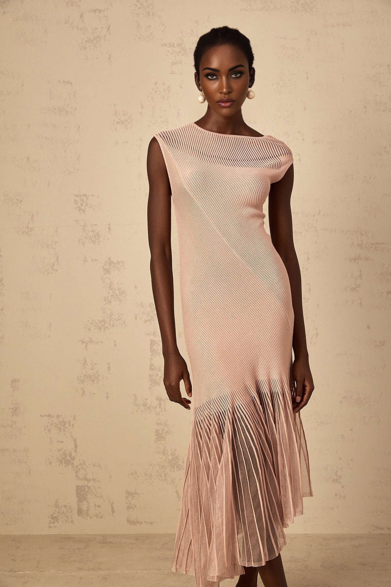 A woman wearing a dusty pink midi dress with a ribbed knit bodice and tulle panel skirt standing in a neutral pose