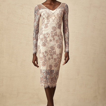 A woman wearing a fitted midi dress made of white guipure lace standing in a neutral background