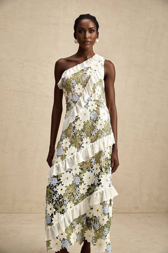 A woman wearing a floral embroidered midi dress with a white background The dress features colorful floral embroidery on a light fabric and has a flowing midi length silhouette