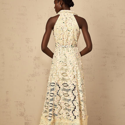A woman wearing a floral embroidered midi dress with cutout details standing in a relaxed pose against a plain background