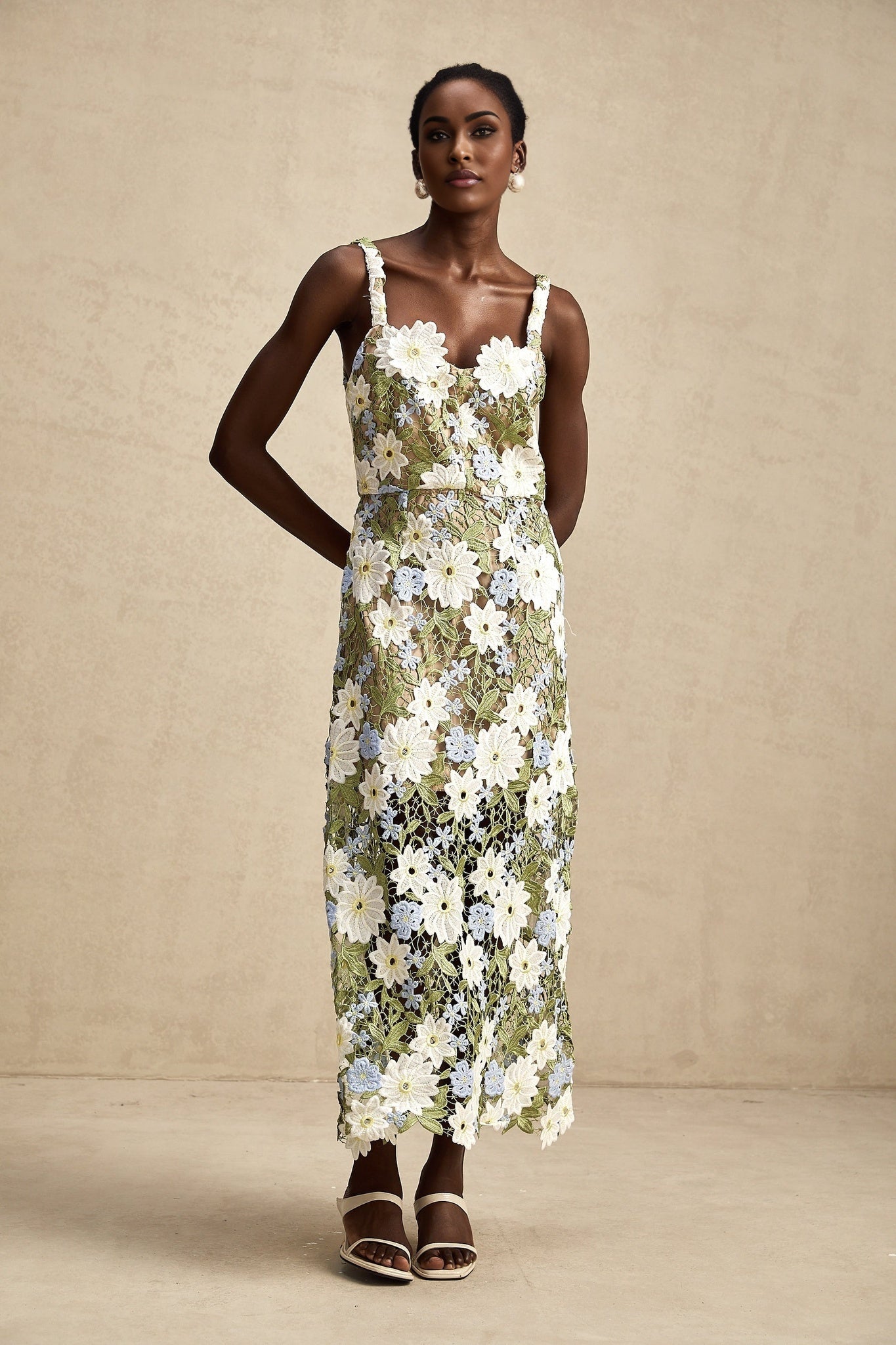 A woman wearing a floral embroidered midi dress with hollow carved details standing in a relaxed pose against a plain background