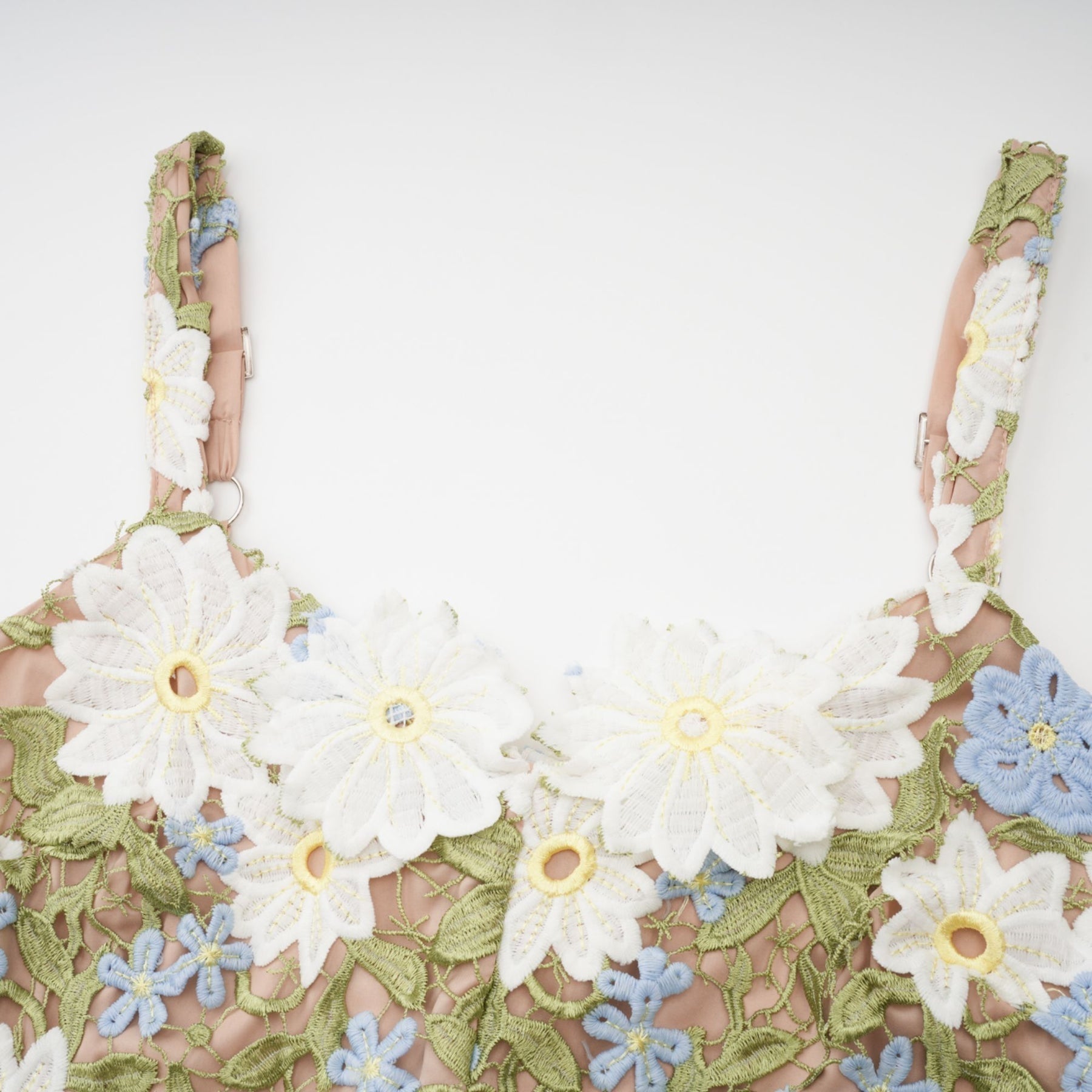 A woman wearing a floral embroidered midi dress with hollow carved details standing in a relaxed pose against a plain background