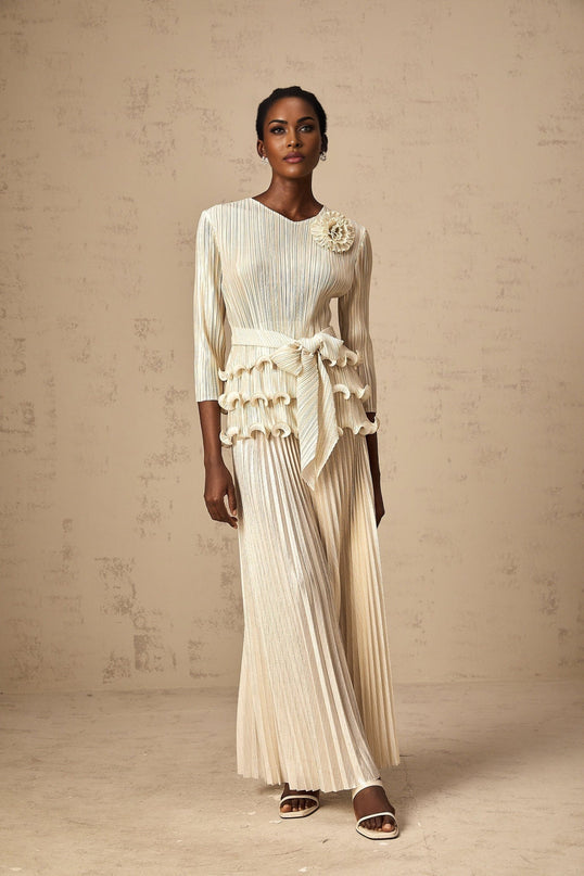 A woman wearing a floral jumpsuit with ruffles and pleats featuring applique detailing