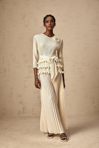 A woman wearing a floral jumpsuit with ruffles and pleats featuring applique detailing