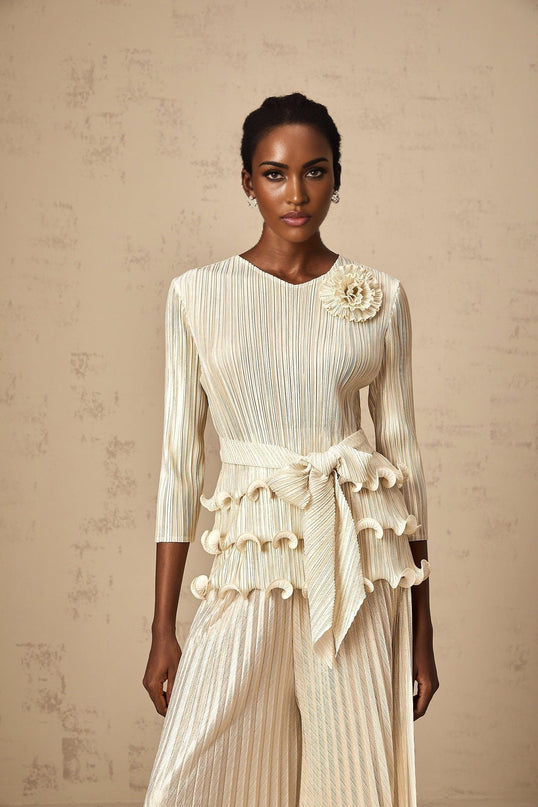 A woman wearing a floral jumpsuit with ruffles and pleats featuring applique flower details