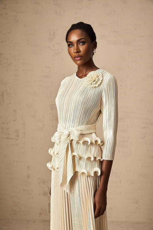 A woman wearing a floral jumpsuit with ruffles and pleats featuring floral applique details