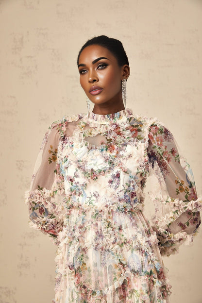 A woman wearing a floral patterned midi dress with ruffled details and a tulle skirt
