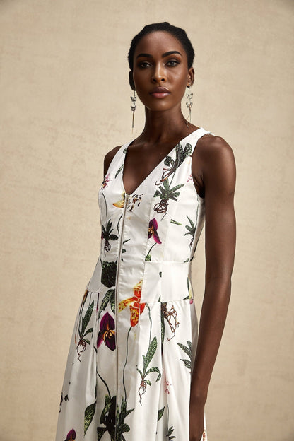 A woman wearing a floral print midi dress with a v neckline and poplin fabric The dress features a colorful floral pattern on a light background and has a flowing skirt that falls to mid calf length