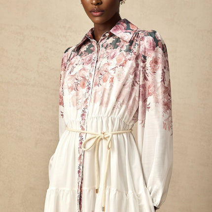 A woman wearing a floral print midi dress with lantern sleeves standing in a relaxed pose against a plain background