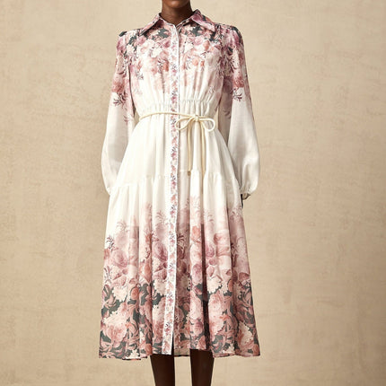 A woman wearing a floral print midi dress with lantern sleeves standing in a relaxed pose