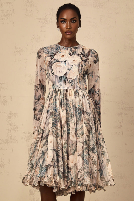 A woman wearing a floral print pleated chiffon midi dress with a flowing silhouette standing against a plain background