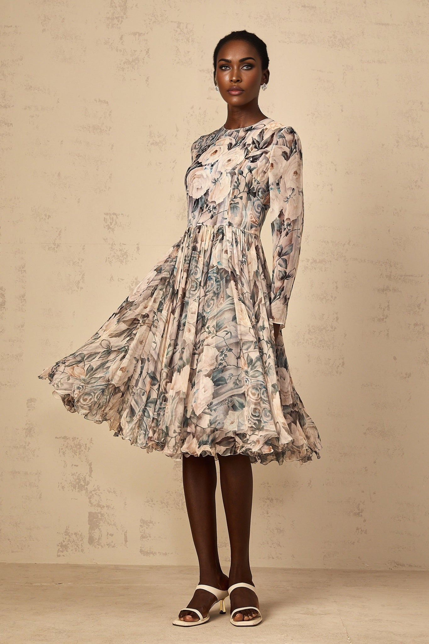 A woman wearing a floral print pleated chiffon midi dress with a light background