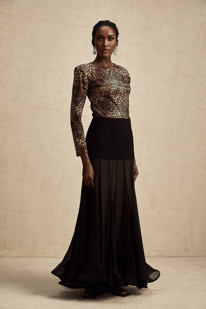 A woman wearing a formfitting leopard print bodysuit with long sleeves and a high neckline