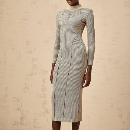A woman wearing a gold ribbed knit midi dress with pointelle details standing in a neutral setting