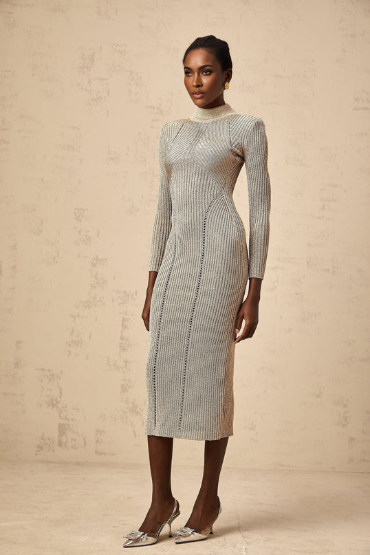 A woman wearing a gold ribbed knit midi dress with pointelle details standing in a neutral setting