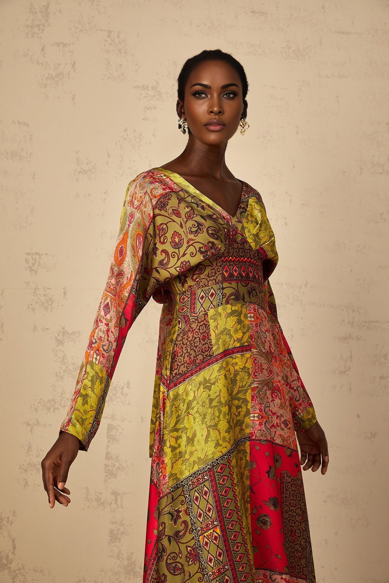 A woman wearing a green floral print midi dress with a flared skirt and short sleeves standing in a relaxed pose
