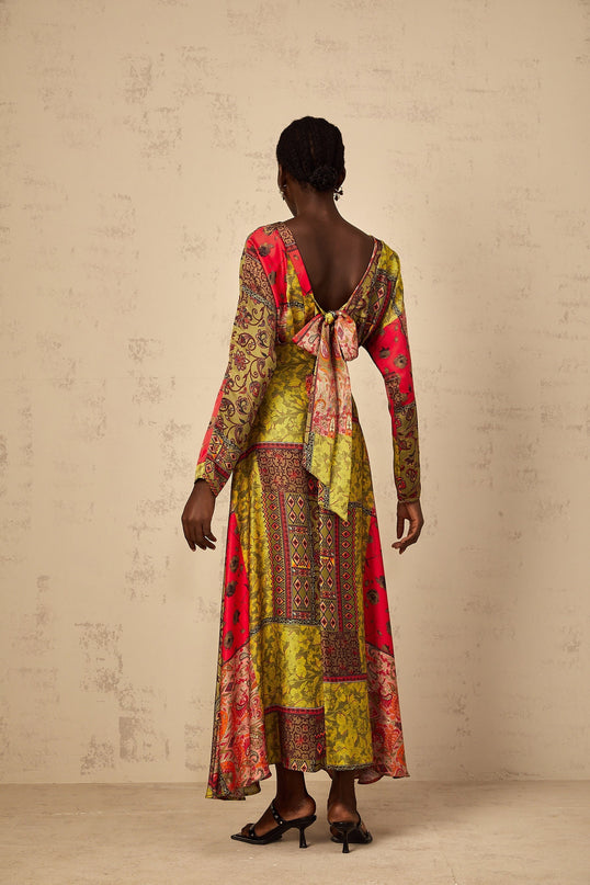 A woman wearing a green floral print midi dress with a flared skirt standing against a plain background