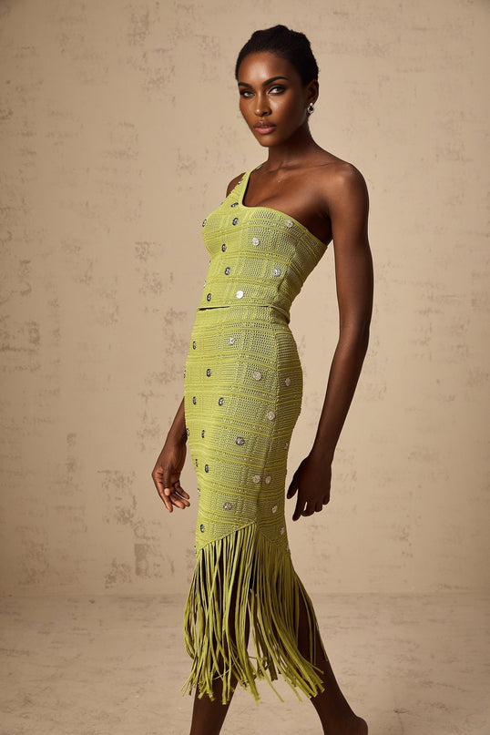 A woman wearing a green knitted two piece outfit consisting of a sleeveless top and matching skirt with embellished details