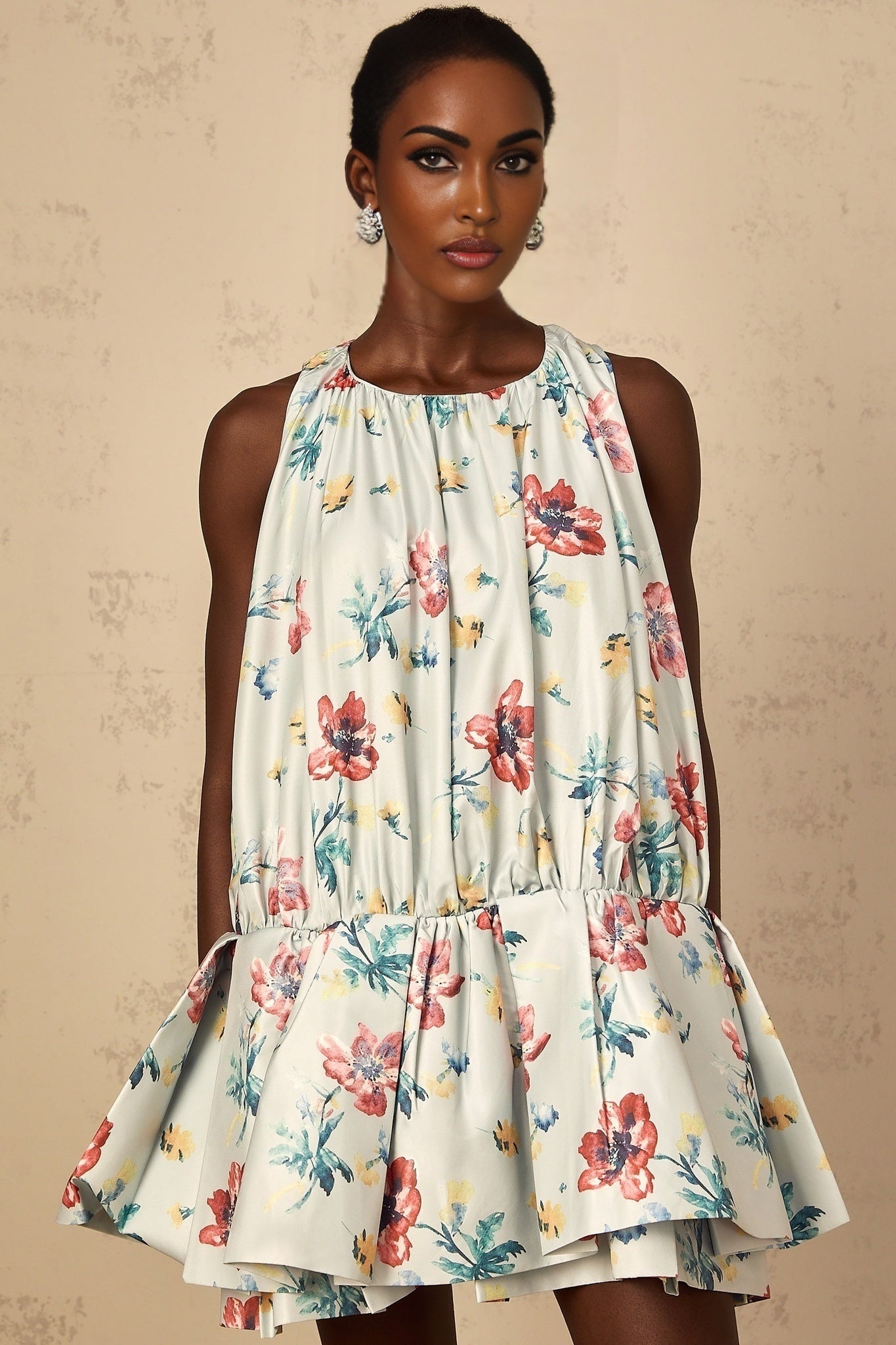 A woman wearing a green mini dress with a floral print pattern and shirred detailing