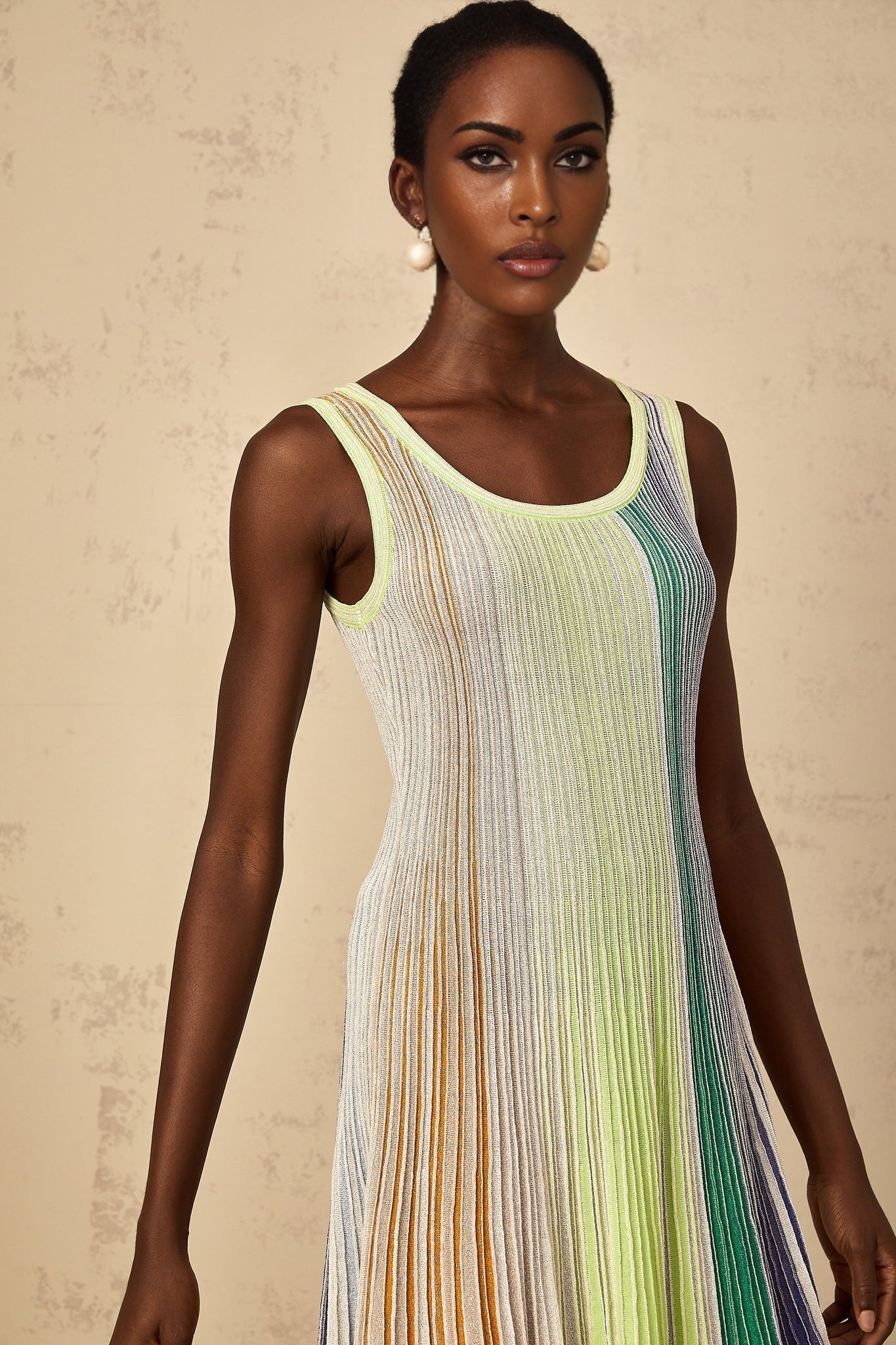 A woman wearing a green mini dress with sequin stripes and a knit texture standing in a neutral pose