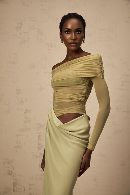 A woman wearing a green offshoulder midi dress with semisheer fabric standing in a relaxed pose