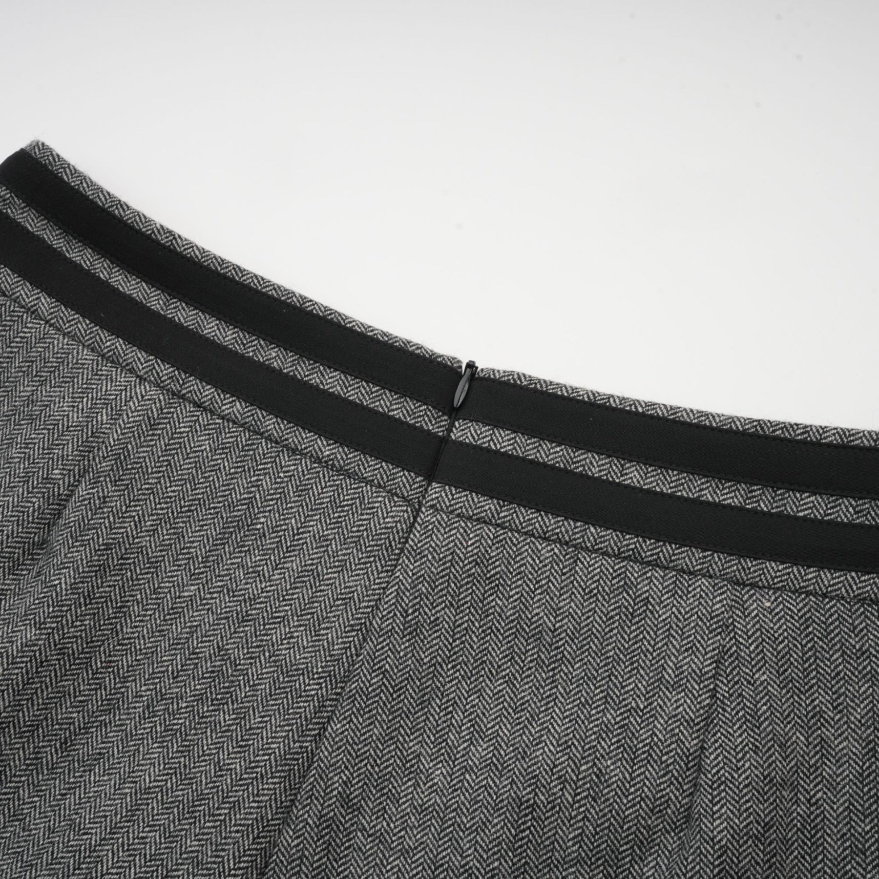 A woman wearing a grey herringbone matching set consisting of a top and shorts standing against a plain background