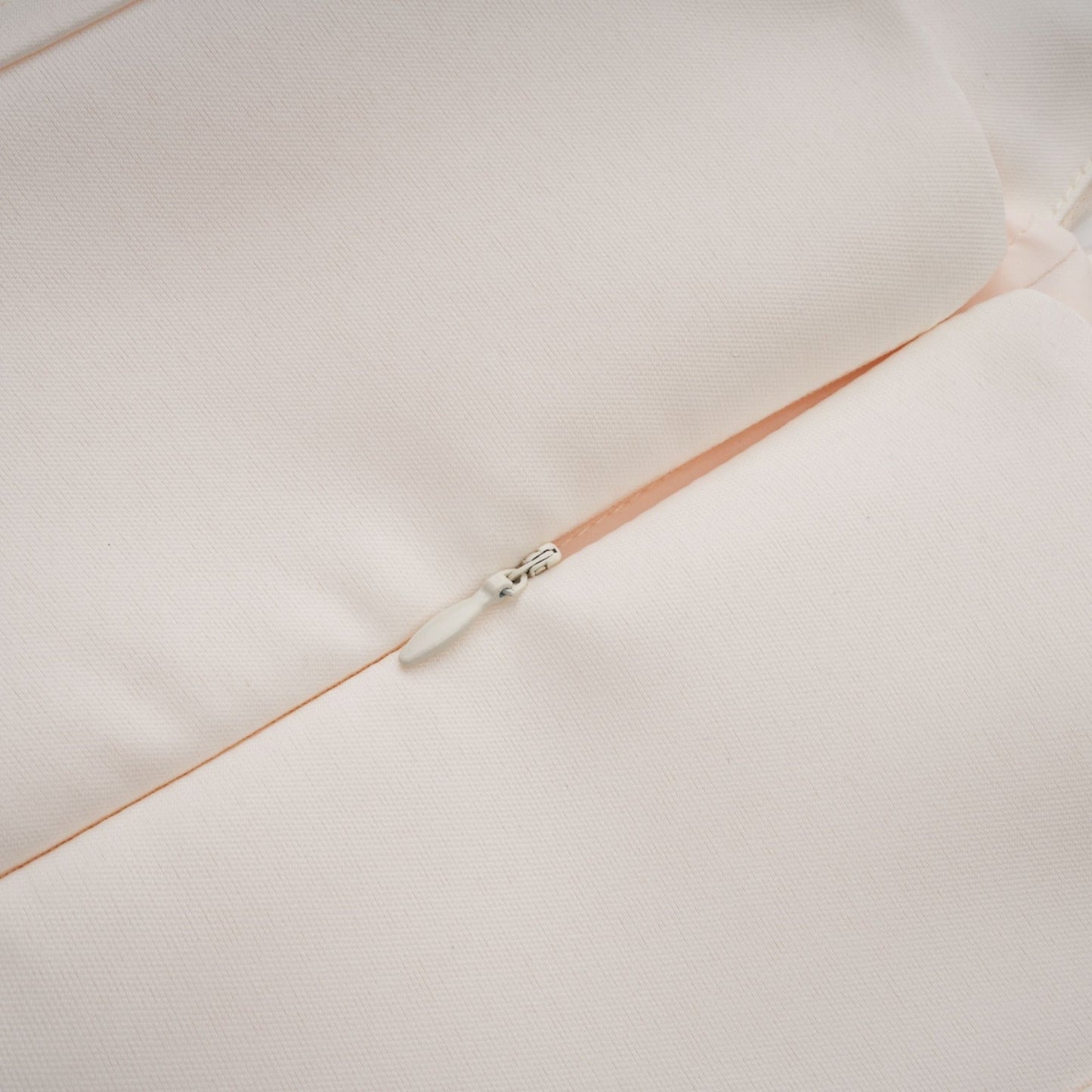 A woman wearing a halterneck tulle midi dress in a light color standing against a plain background
