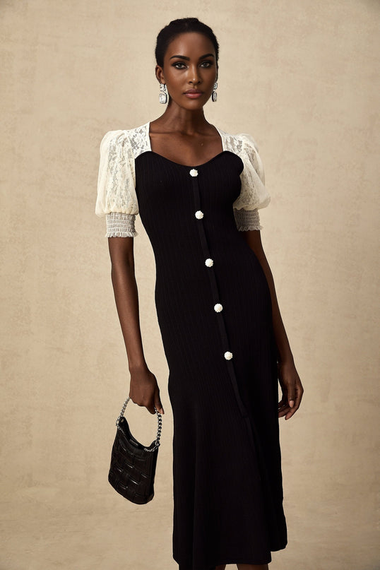 A woman wearing a knit midi dress with lace trim details along the neckline and hem standing in a neutral pose against a plain background