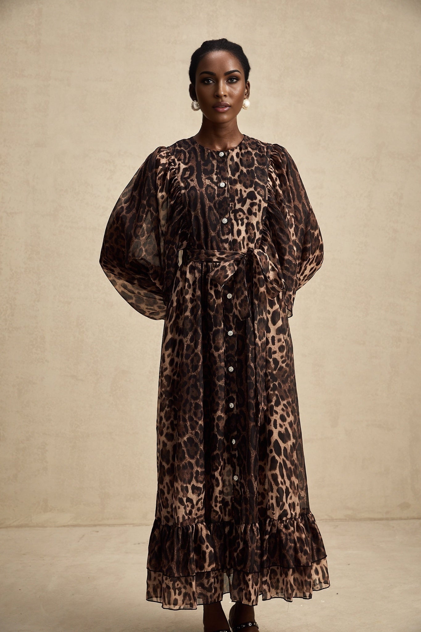 A woman wearing a leopard print midi dress with a single breasted design and a fitted silhouette standing in a neutral pose