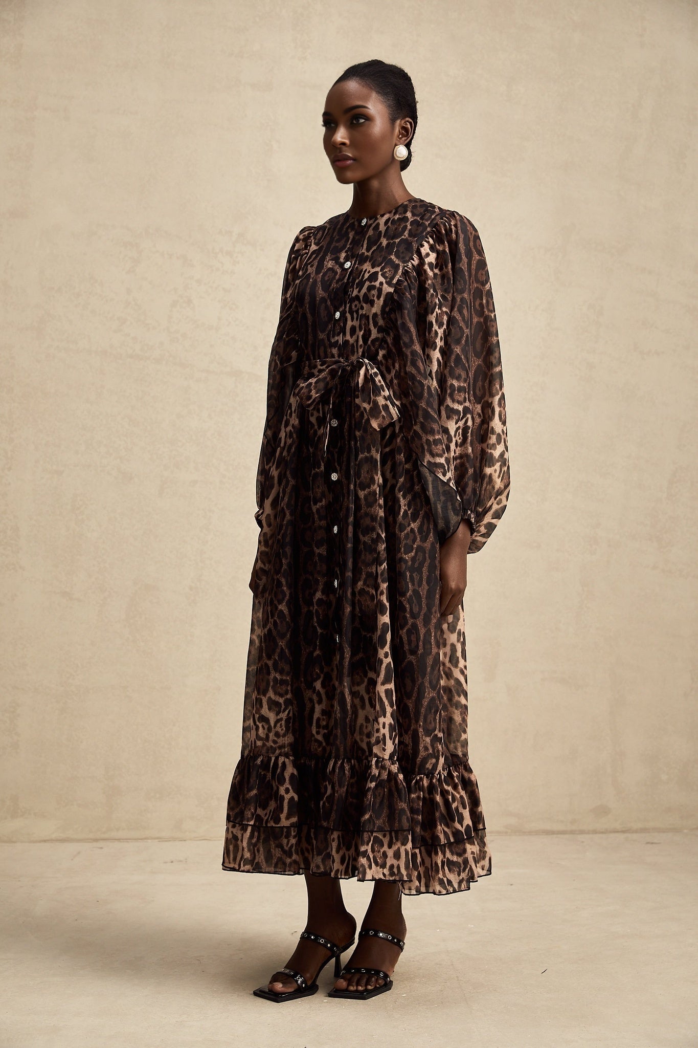 A woman wearing a leopard print midi dress with a single breasted design and a fitted silhouette