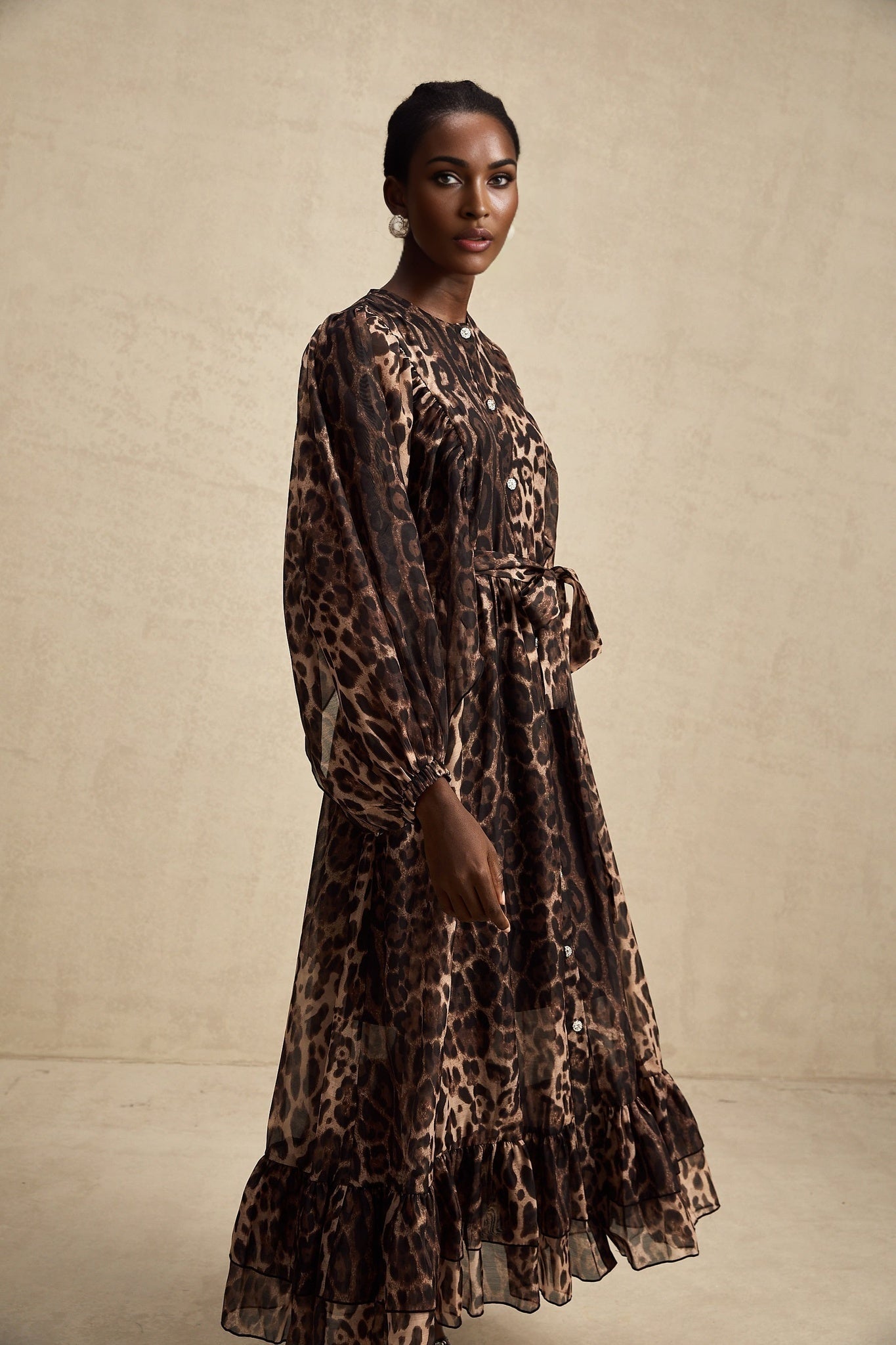 A woman wearing a leopard print midi dress with a single breasted design featuring the Gisele style