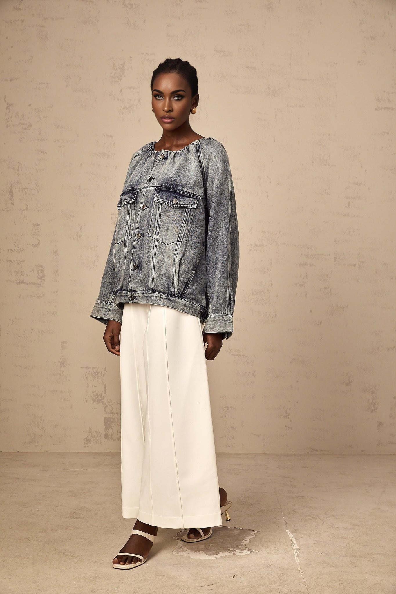 A woman wearing a light blue collarless denim jacket with long sleeves and buttoned front