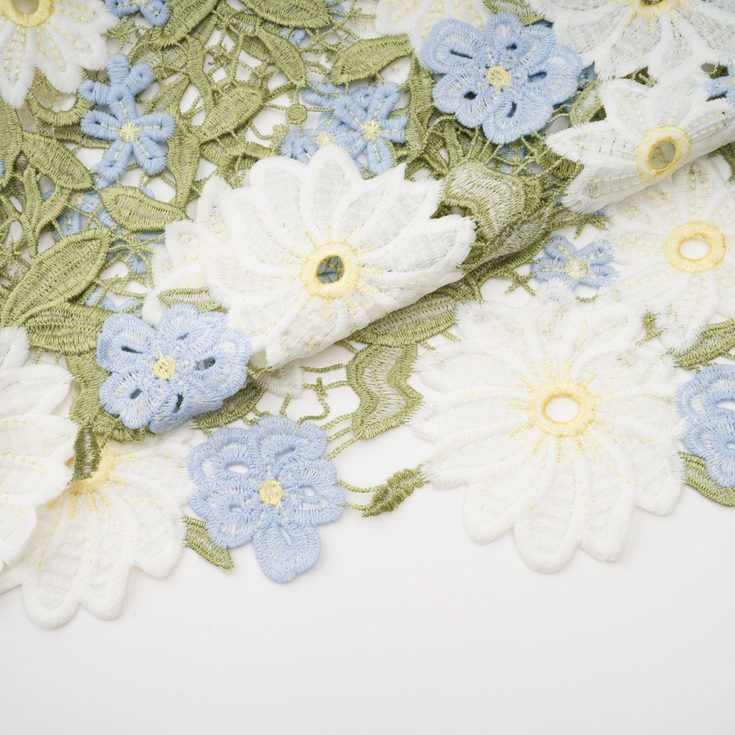 A woman wearing a lightcolored midi dress with floral embroidery and cutout details standing in a natural outdoor setting