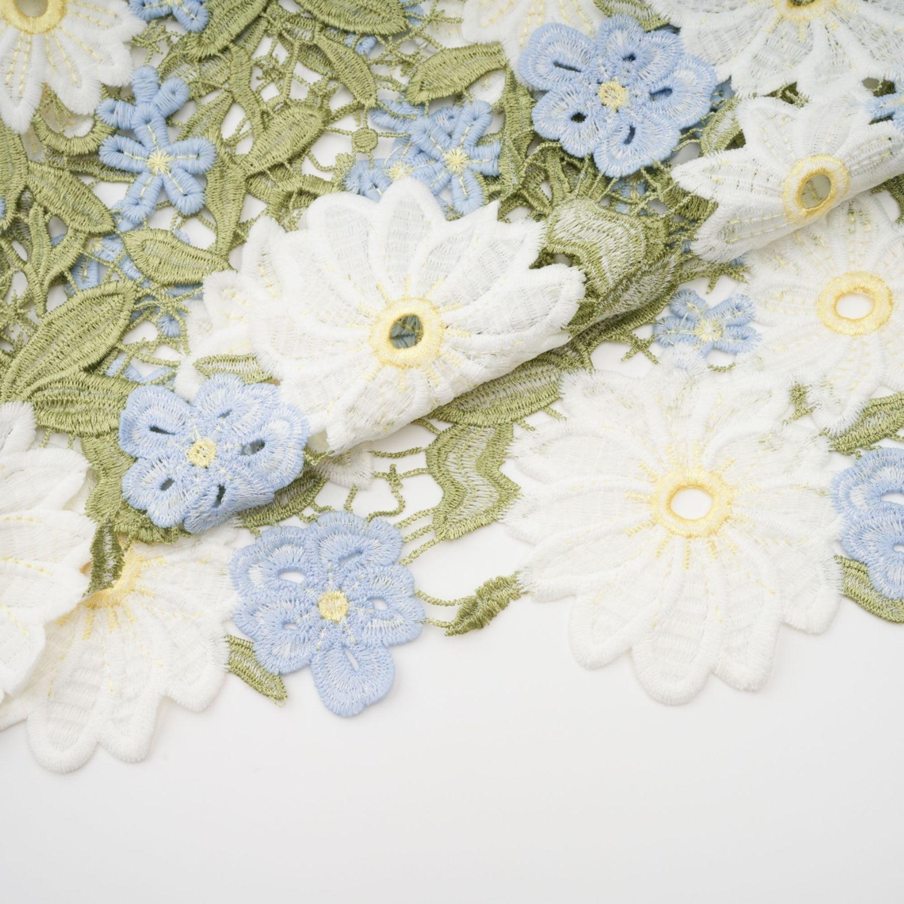 A woman wearing a lightcolored midi dress with floral embroidery and cutout details standing in a natural outdoor setting