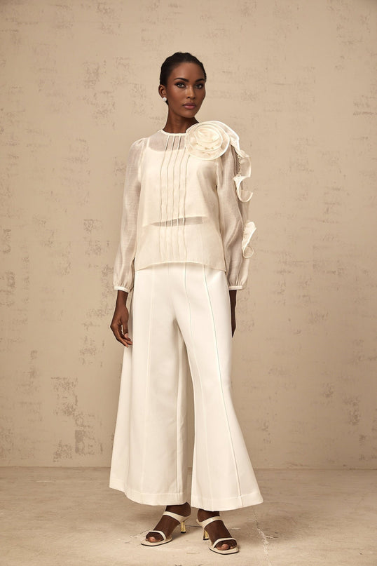 A woman wearing a lightcolored sheer blouse with delicate three dimensional floral details