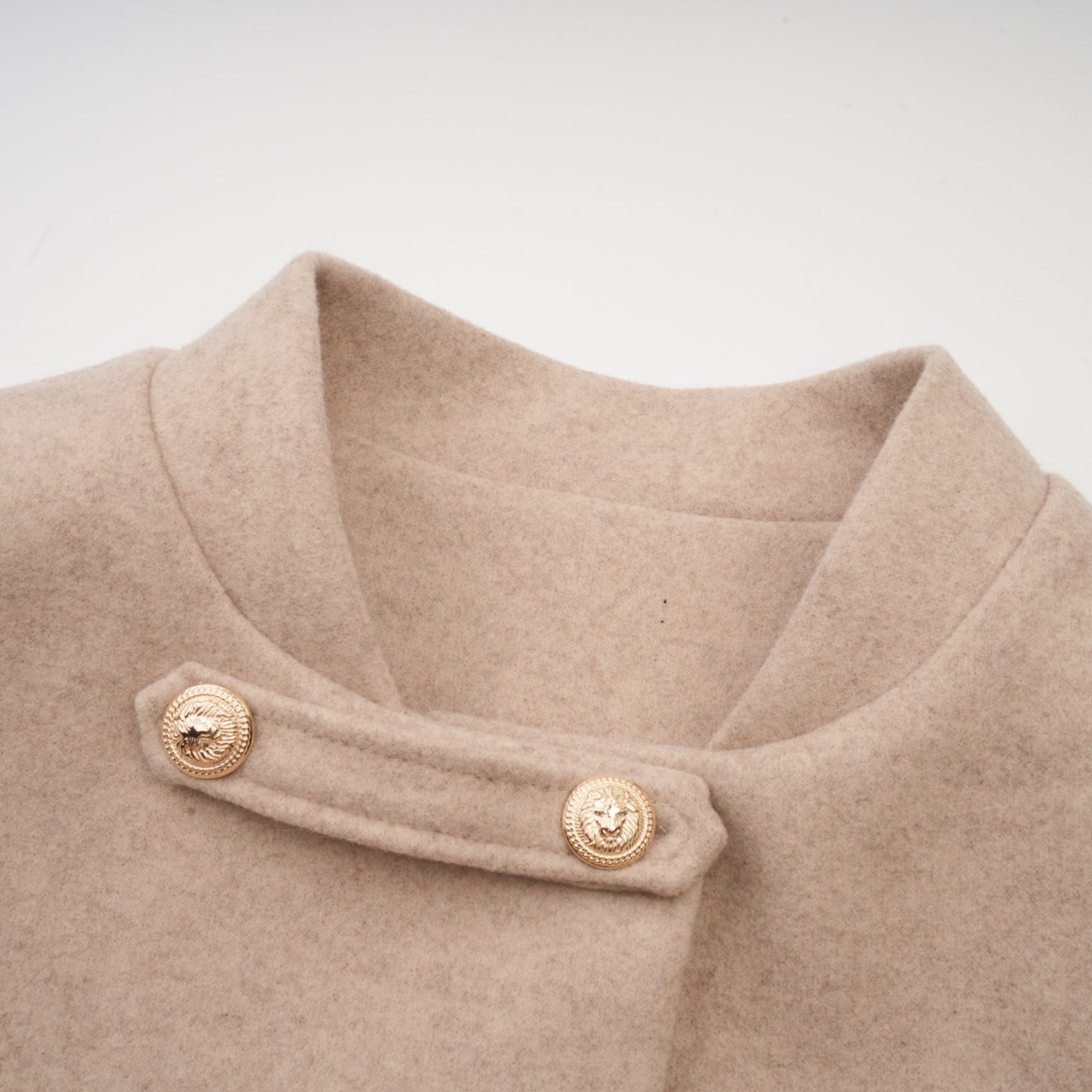 A woman wearing a long black coat with a detachable faux fur cape collar standing in an elegant pose