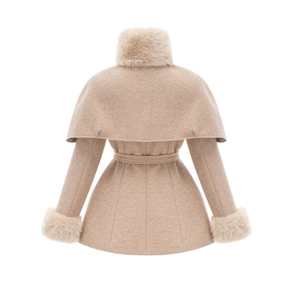 A woman wearing a long black faux fur coat with a detachable cape around the shoulders standing in a stylish pose