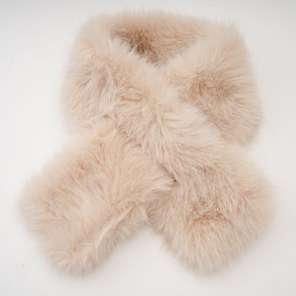 A woman wearing a long black faux fur coat with a detachable cape collar standing against a plain background