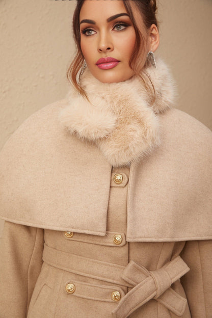 A woman wearing a long black faux fur coat with a detachable cape collar standing in a stylish pose