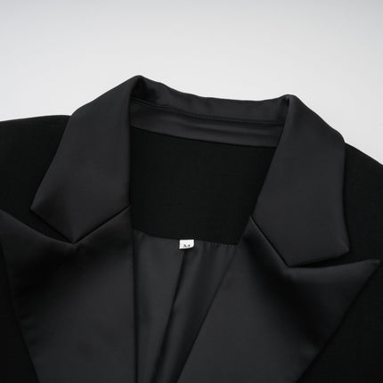 A woman wearing a long black maxi blazer dress with embellished details standing in a relaxed pose