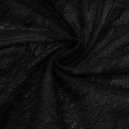 A woman wearing a long black maxi dress with a single shoulder strap and a cutout detail on one side