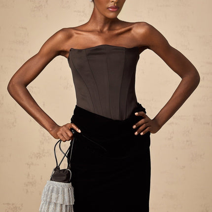 A woman wearing a long black velvet off shoulder maxi dress standing in an elegant pose
