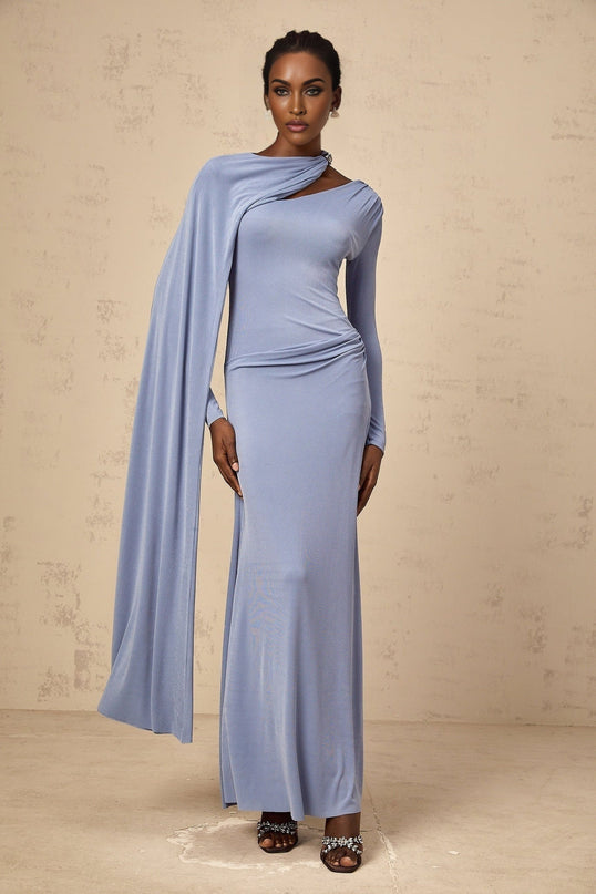 A woman wearing a long blue fitted maxi dress with a diagonal shawl detail across the bodice