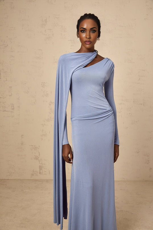 A woman wearing a long blue fitted maxi dress with a diagonal shawl neckline and sleeves