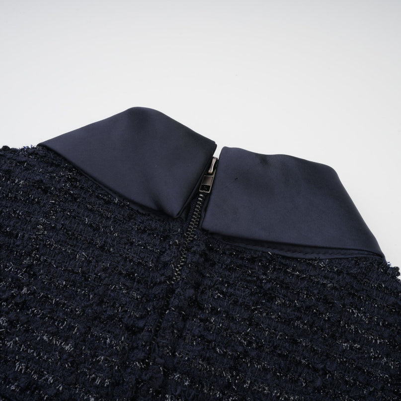 A woman wearing a long blue maxi dress with a fitted peplum waist and panelled design standing against a plain background