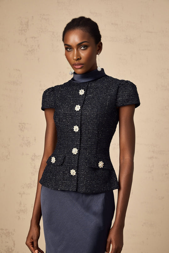 A woman wearing a long blue maxi dress with a fitted peplum waist and panelled design standing in a relaxed pose