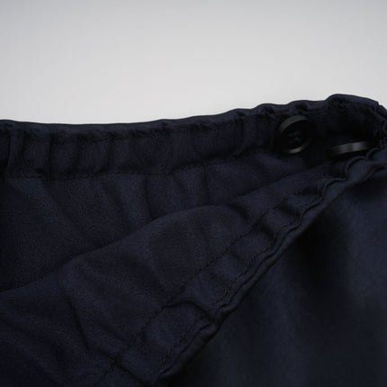 A woman wearing a long blue maxi dress with a fitted peplum waist and panelled design standing in a relaxed pose